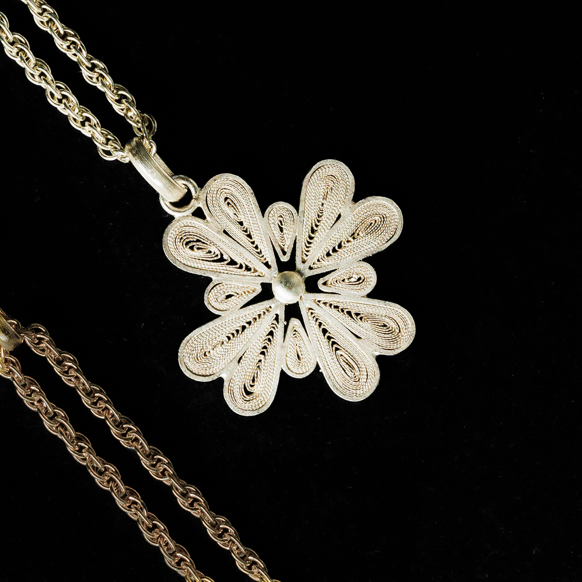 Close-up of handmade 950 silver filigree flower pendant necklace by Oh Voila Jewelry, displayed on a black velvet background.

